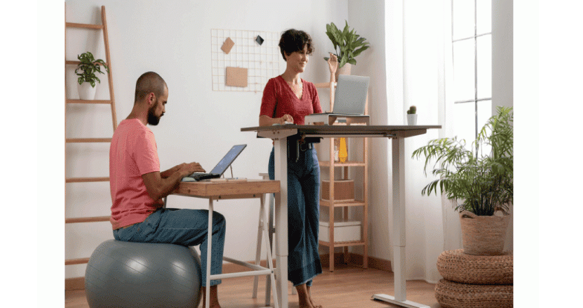 homme assis sur ballon et femme debout a un bureau